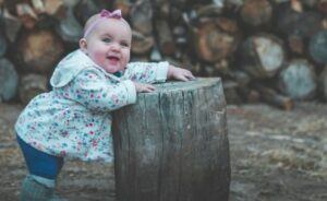 Trends in used baby cloths-Baby IN Jacket standing by tree stump