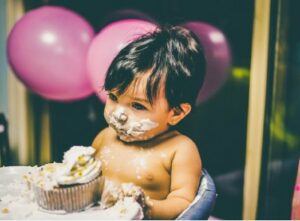 Babies first birthday clothing-Baby enjoying birthday cake