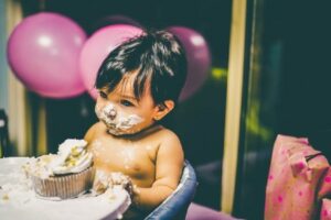 Babies' first birthday clothing-Baby enjoying birthday cake.