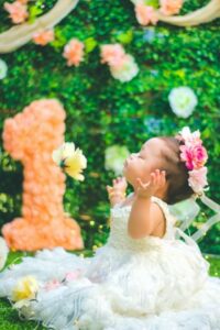 Babies first birthday clothing-Baby girl on first birthday wearing white dress and pink flowers in hair