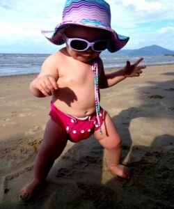 Best infant sunglasses -Baby walking on the beach wearing Cancer council sunglasses