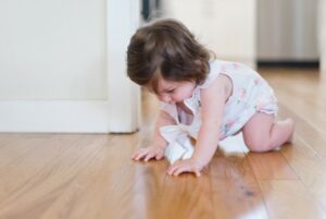 Affordable organic baby clothes in Australia-Baby crawling on a wooden floor.