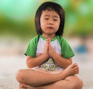 Teaching law of attraction to children-Young child meditating