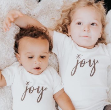 Best Organic Christmas onesies for infants- Baby and toddler wearing matching Christmas onesie and tees stating 'Joy".