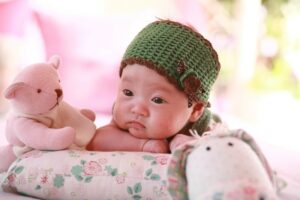Organic baby clothes for girl's-Baby resting chin on arm wearing a dark green headband.