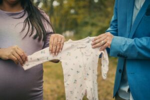 Would you consider renting the baby clothes for a newborn?-Parents to be holding a newborn baby suit.