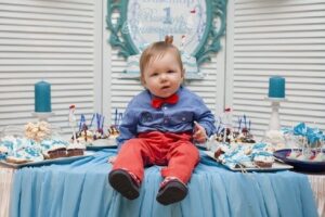 Babies' first birthday clothing-Cute baby sitting on the table on his first birthday-Baby on his firstbirthday sitting on the snack table.