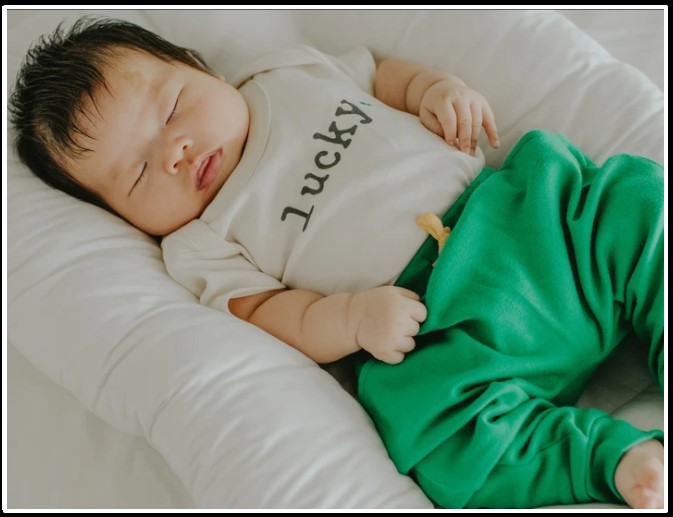 Trendy baby clothes for boys-Baby wearing gender neutral organic outfit with graphic stating 'lucky'.