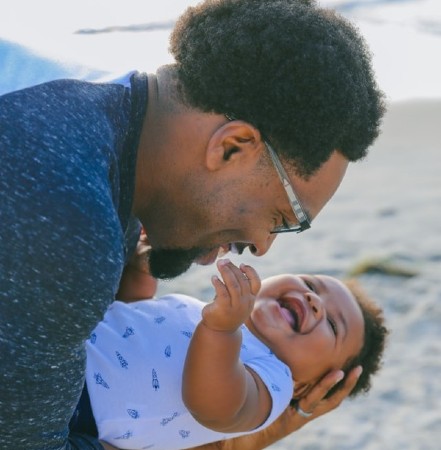 What's Simple Joys by Carter's?-Father holding a smiling baby on the beach.