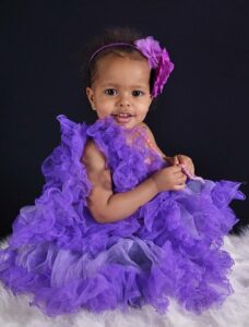 What're Designer baby clothes?-Little girl dressed up in a purple dress.