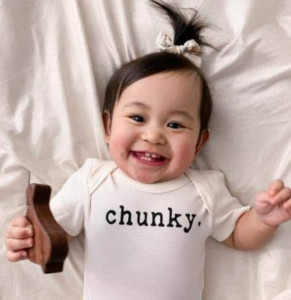 Are Finn and Emma's baby clothes on Amazon?- Smiling baby wearing a Finn and Emma graphic bodysuit stating 'Chunky".